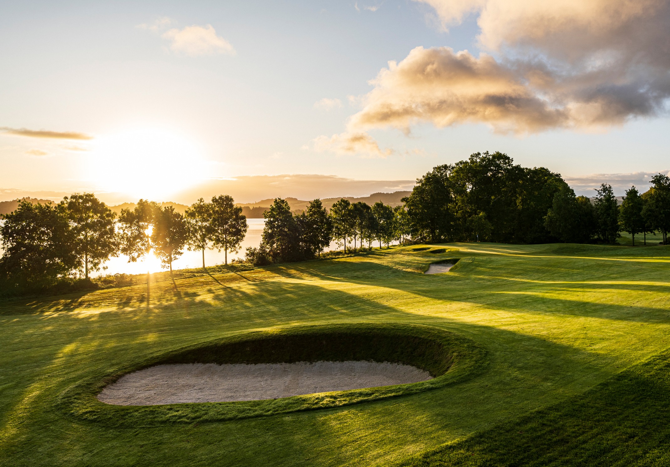 The sun setting behind the trees at the Carrick Golf Course