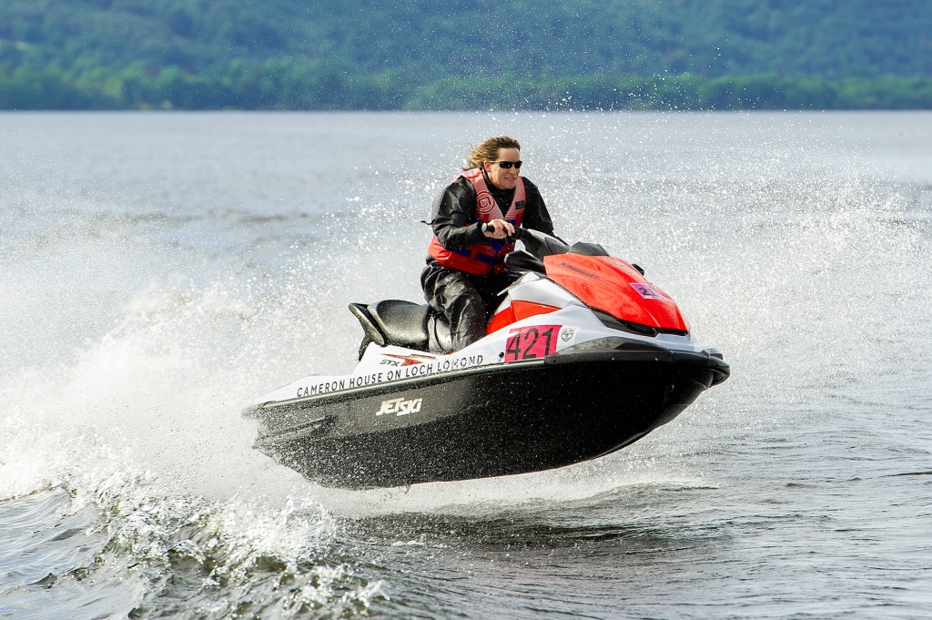 a person riding a white and red jet ski jumping over the waves in the middle of the lake