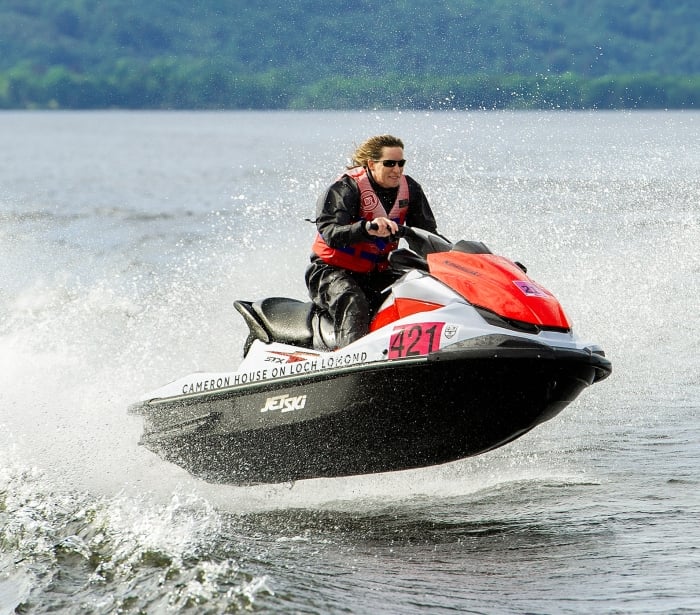 a person riding a white and red jet ski jumping over the waves in the middle of the lake