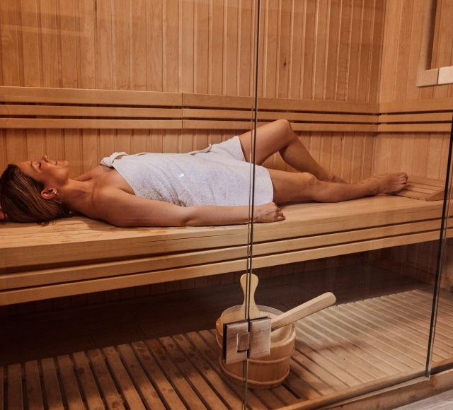 a woman wrapped in a towel laying in a infrared sauna