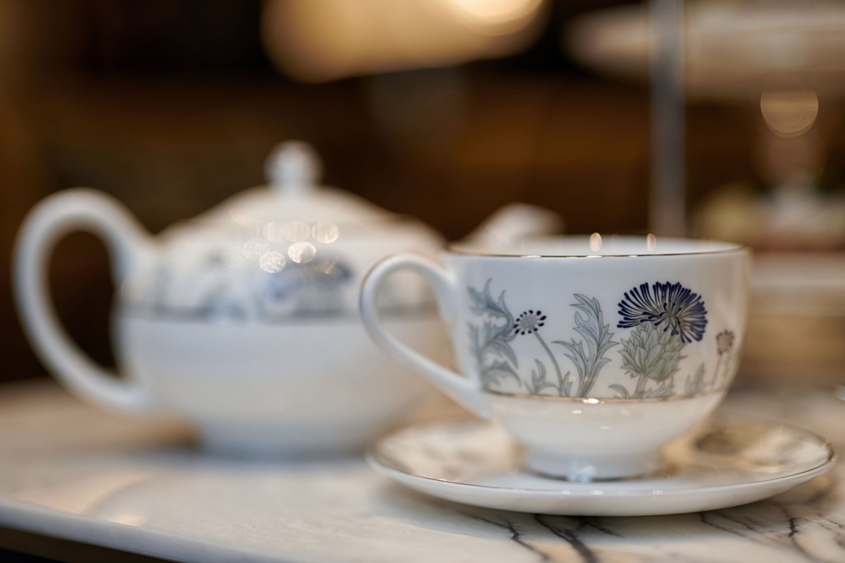 a close up view of a tea cup with a tea pot in the back ground