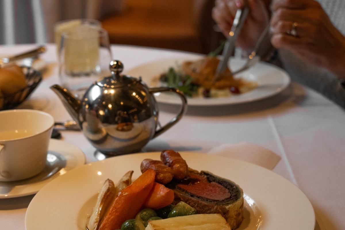 A woman sitting at a table with a plate of beef wellington.