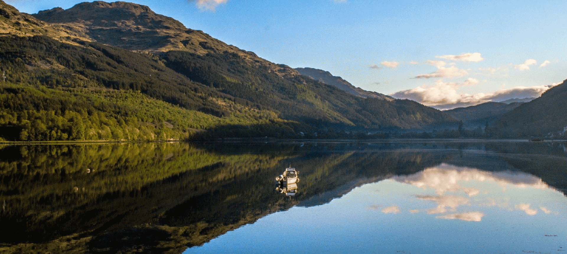 a boat out on a large body of water with massive mountains in the back ground