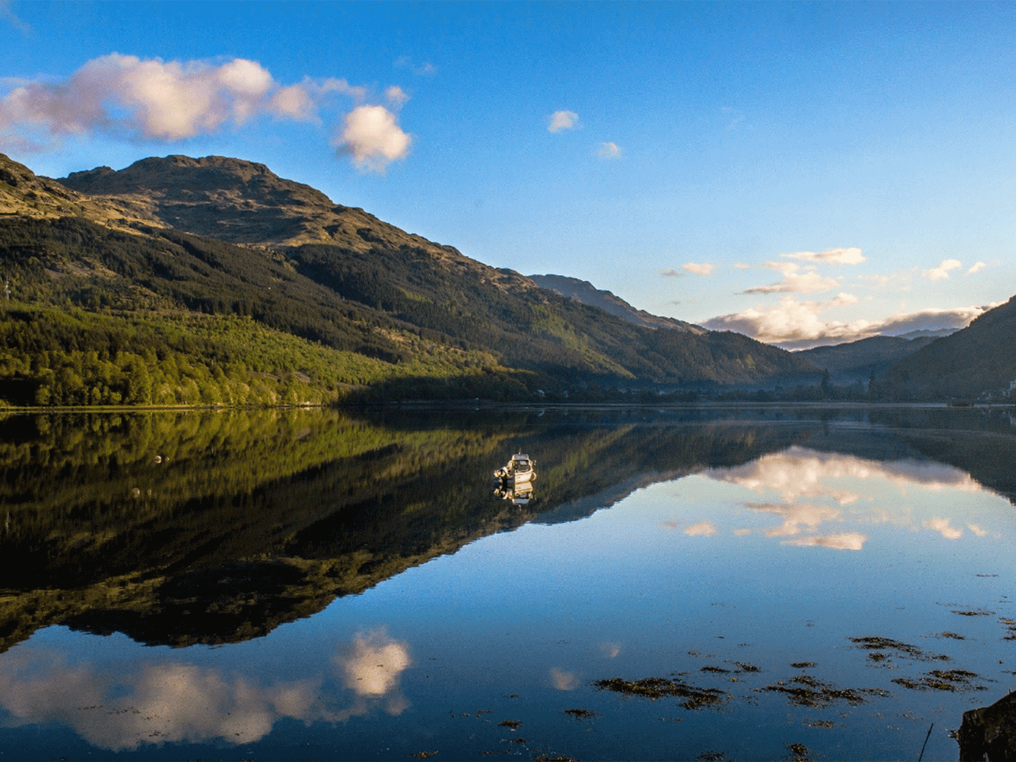a boat out on a large body of water with massive mountains in the back ground