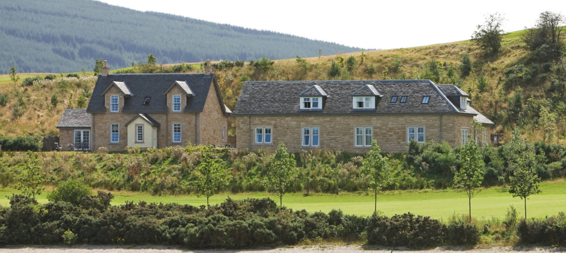 two cottages sitting lake side with hills sitting in the background