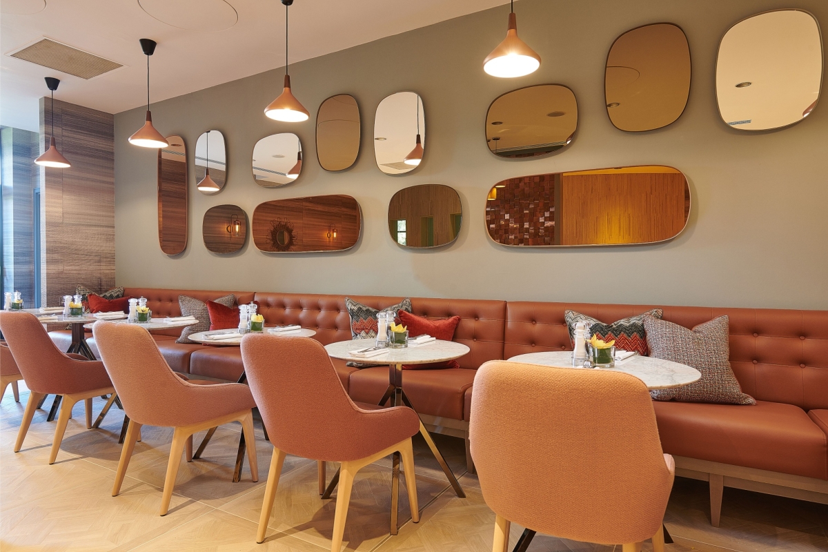 tables and booth seats against a wall with mirrors above