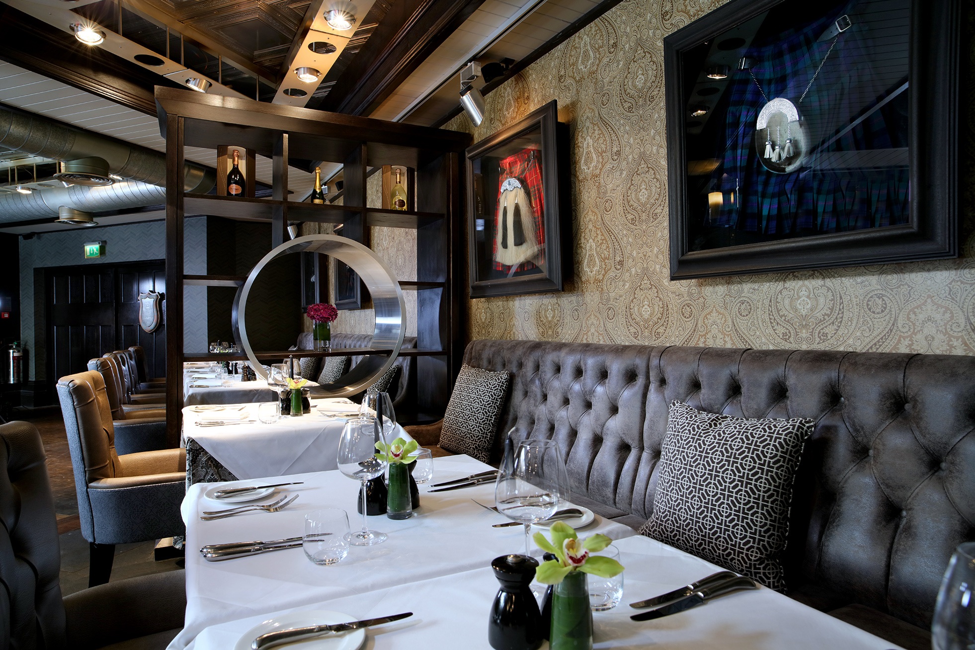 dining table with white covers and chairs with kilts on the wall behind them