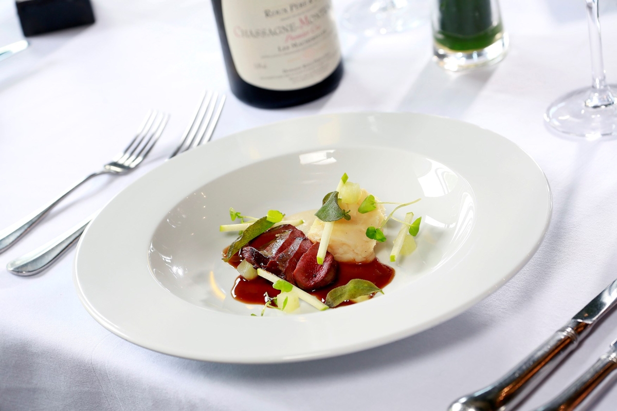 sliced up duck sitting on a plate with colourful garnish