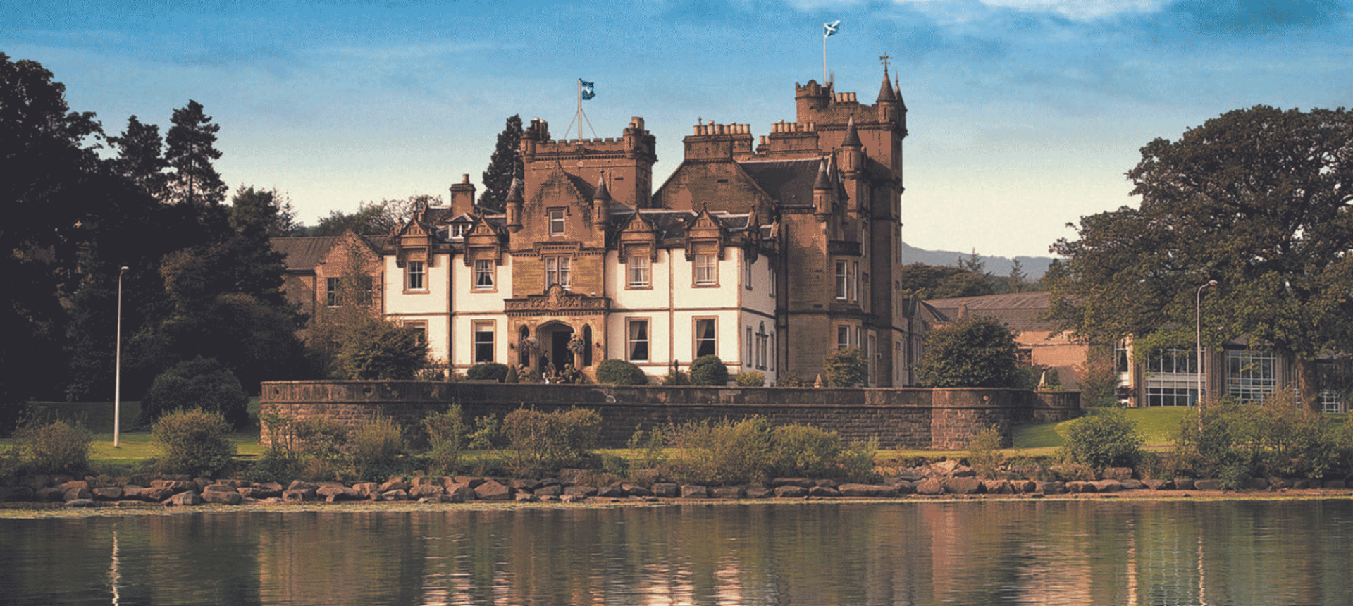 a large old style building sitting on the edge of water with cloud above