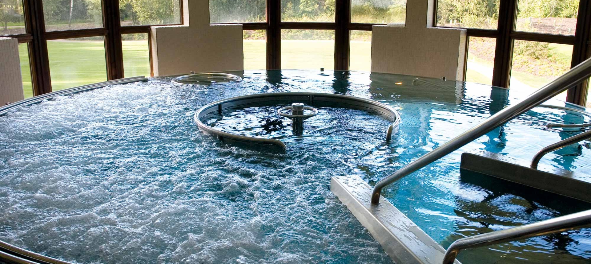 a large whirl pool with windows looking outside at the trees