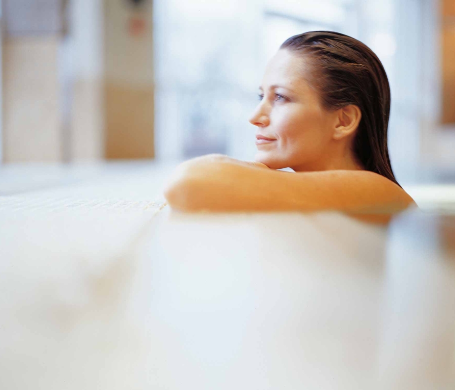 a woman sitting in a pool leaning on the edge looking outside