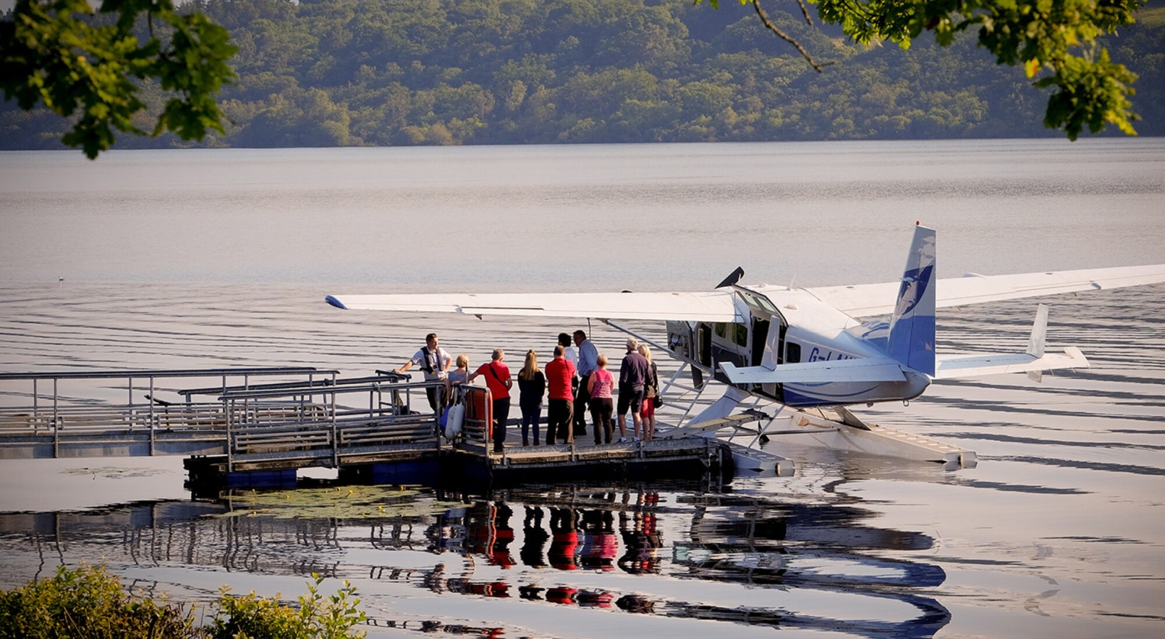 a group of people standing next to a sea plane docked on the water