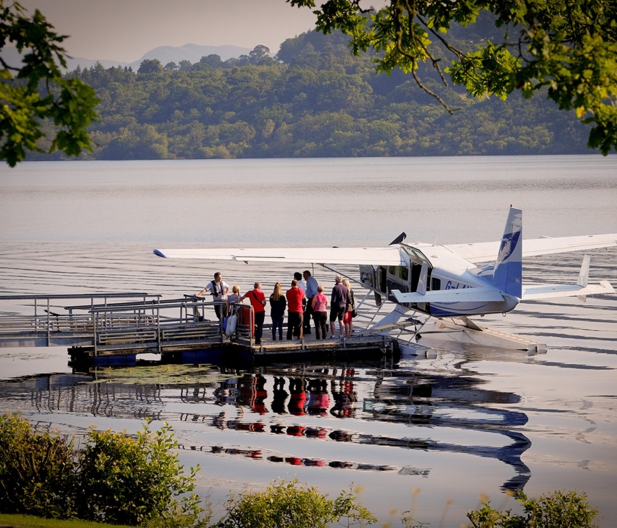 a group of people standing next to a sea plane docked on the water