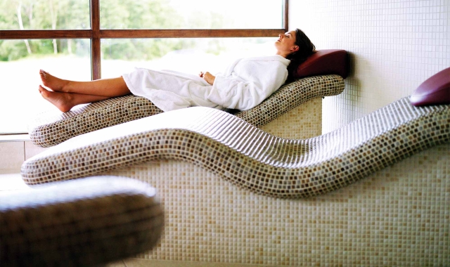 a woman laying down in a robe relaxing on a spa bed