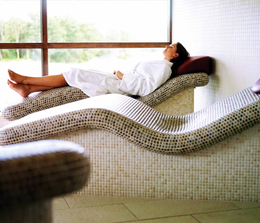 a woman laying down in a robe relaxing on a spa bed