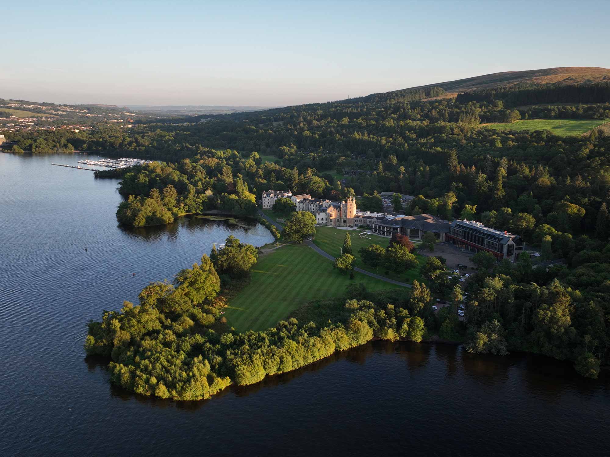 a birds eye view of cameron house with lots of trees and hills behind it