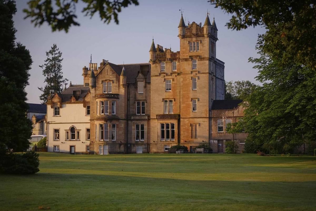 exterior view of a large castle like building sitting on lush green grass