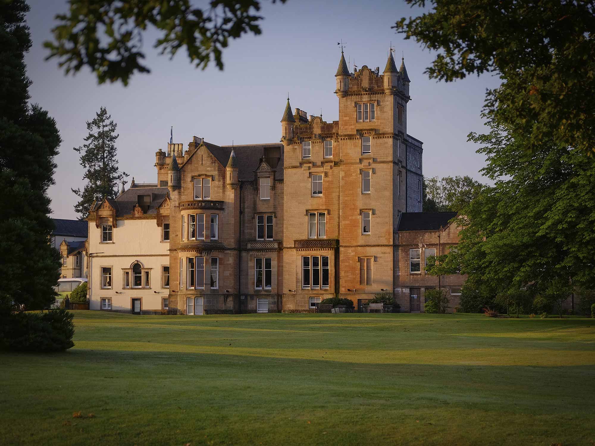 exterior view of a large castle like building sitting on lush green grass