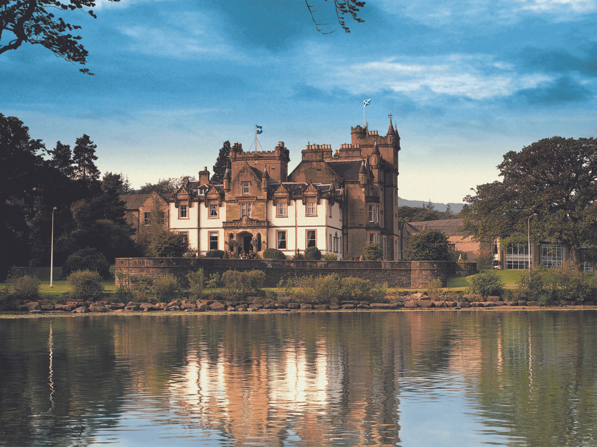 a large old style building sitting on the edge of water with cloud above