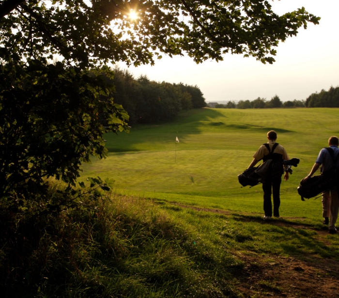 Two golfers walking down the fairway into the sunset at The Carrick championship golf course at Cameron House Loch Lomond