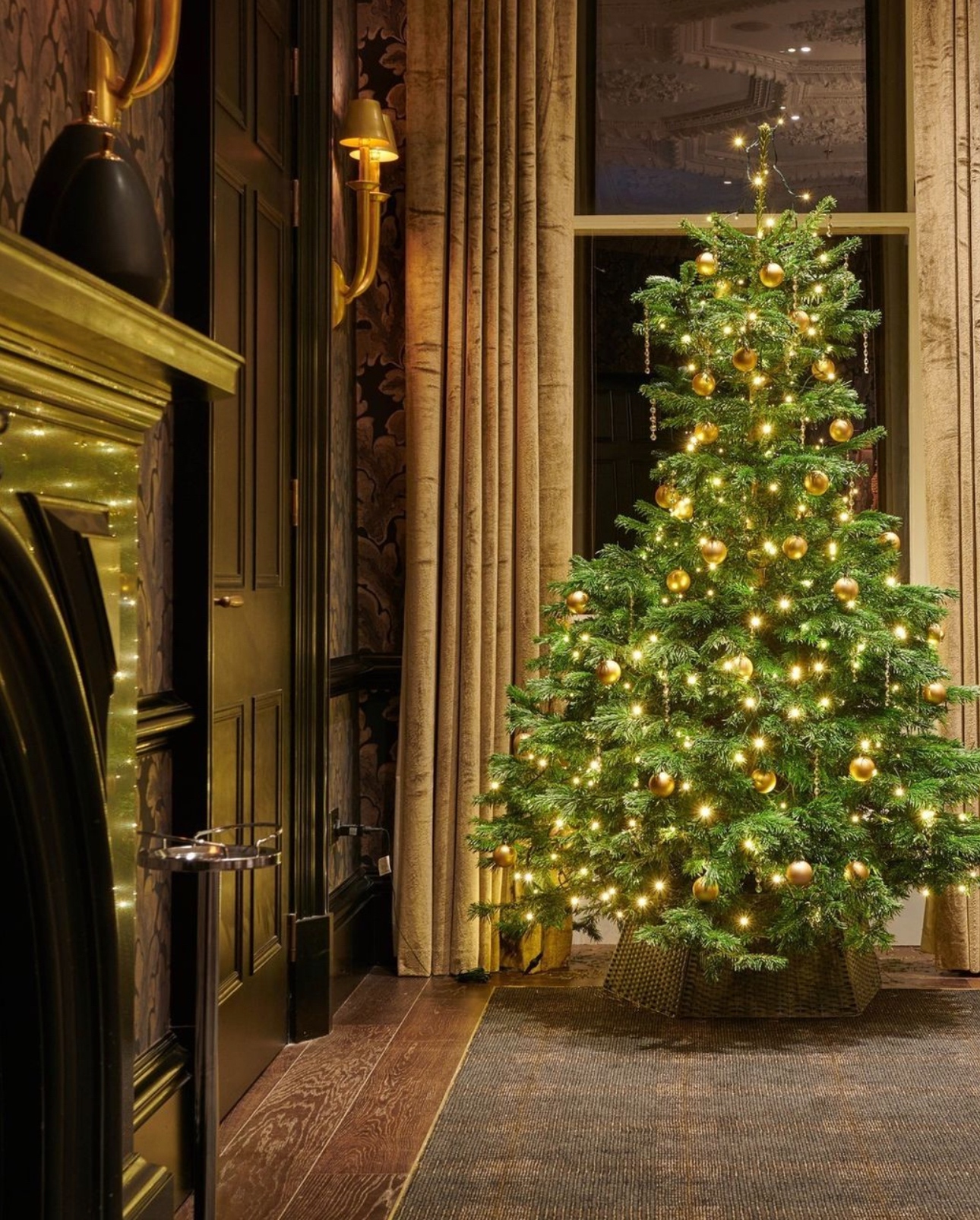 A beautifully decorated Christmas tree standing in a room with a crackling fireplace, spreading holiday cheer