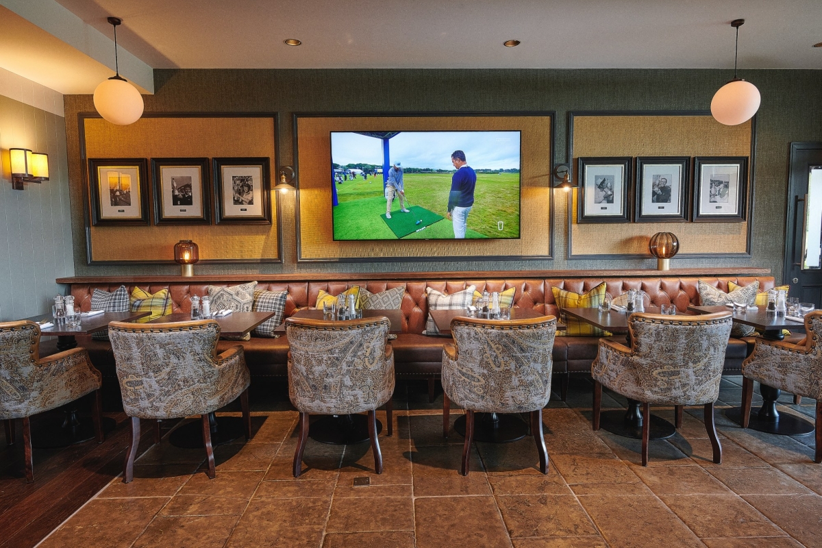 Table and chairs set up for service with a tv playing golf in the back