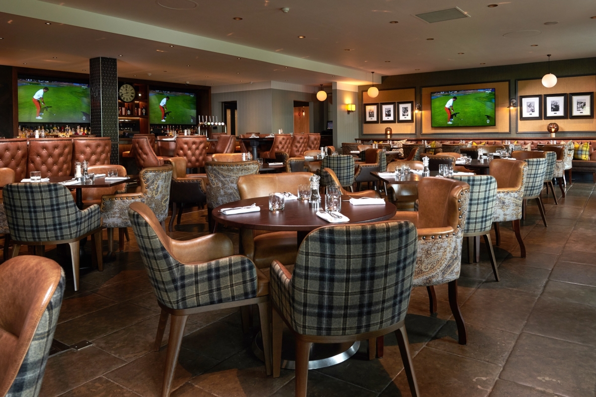 dining room filled with tables and chairs for dinner service and tvs playing golf in the back