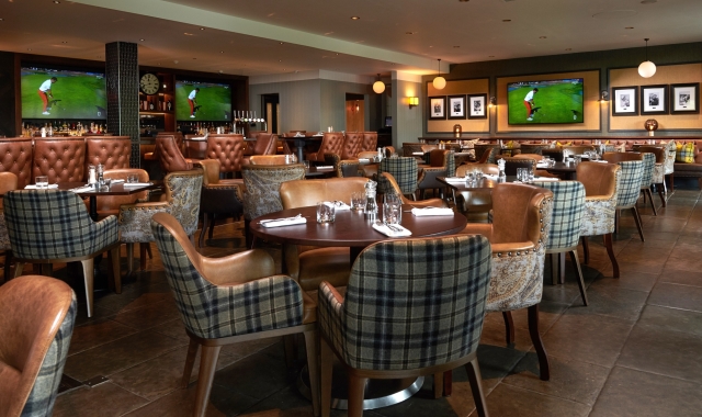 dining room filled with tables and chairs for dinner service and tvs playing golf in the back