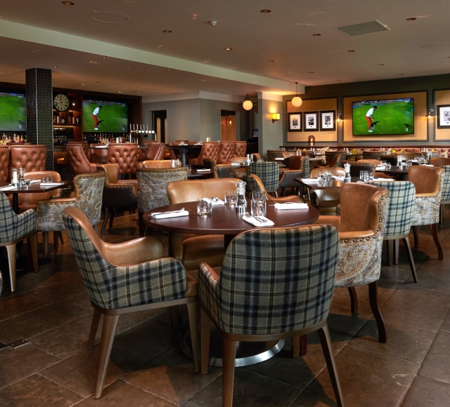 dining room filled with tables and chairs for dinner service and tvs playing golf in the back