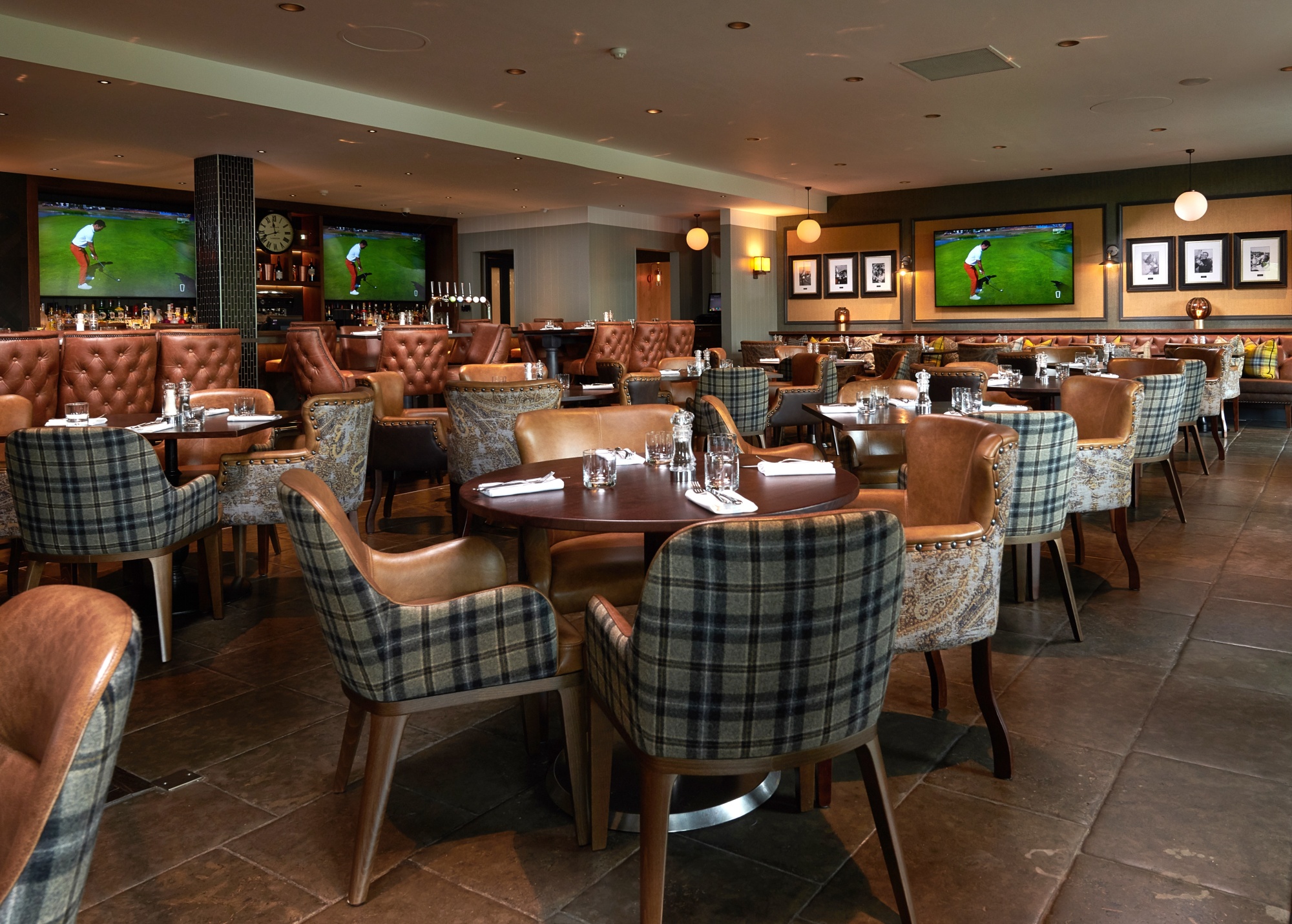 dining room filled with tables and chairs for dinner service and tvs playing golf in the back