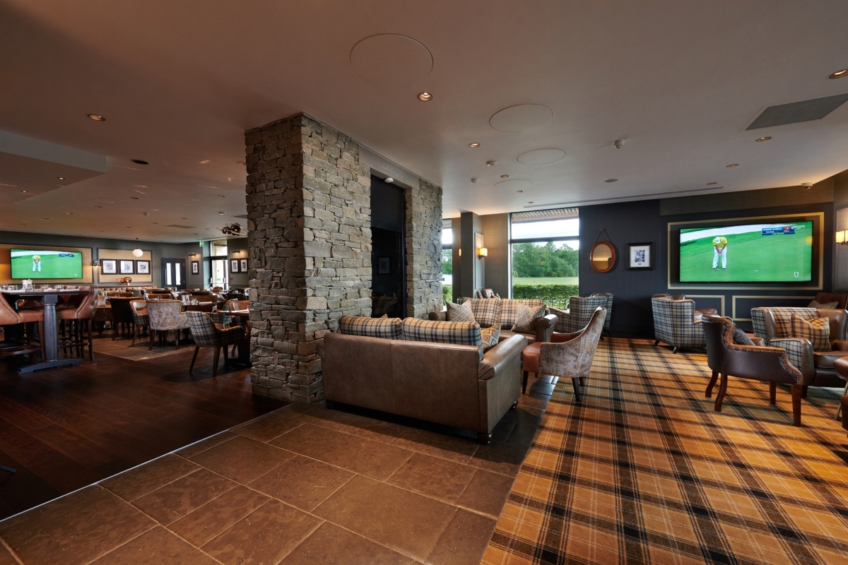 seating area inside with multiple chairs and tables with tv's playing golf