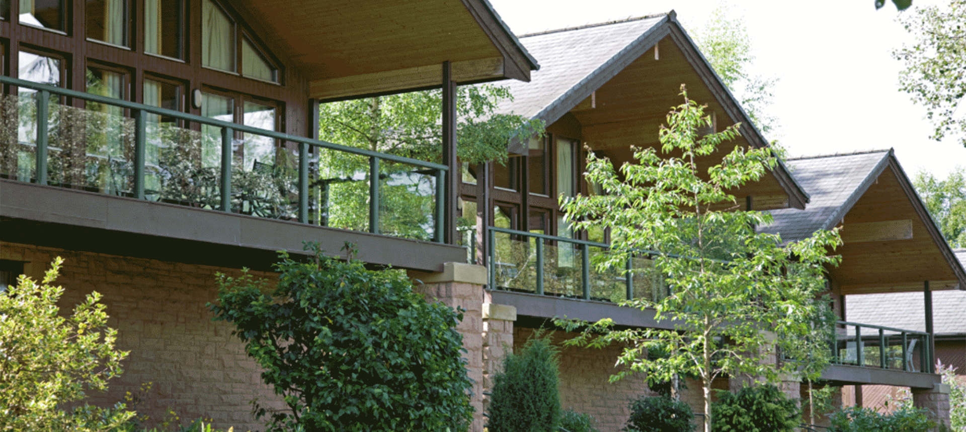 three cottages with trees below them and stairs leading up to the entrance