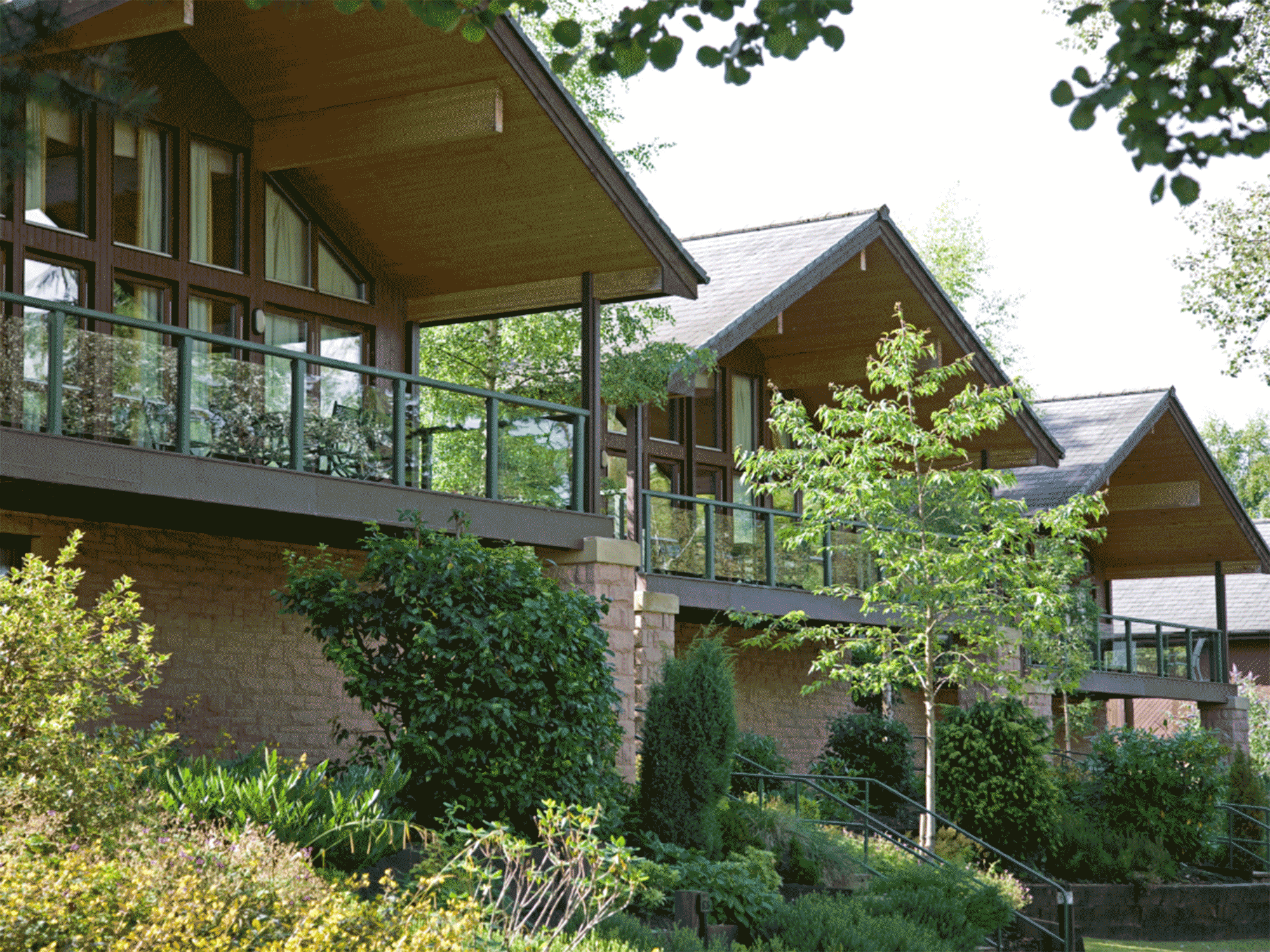 three cottages with trees below them and stairs leading up to the entrance