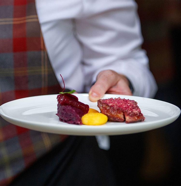 food sitting on a while plate being help by a server