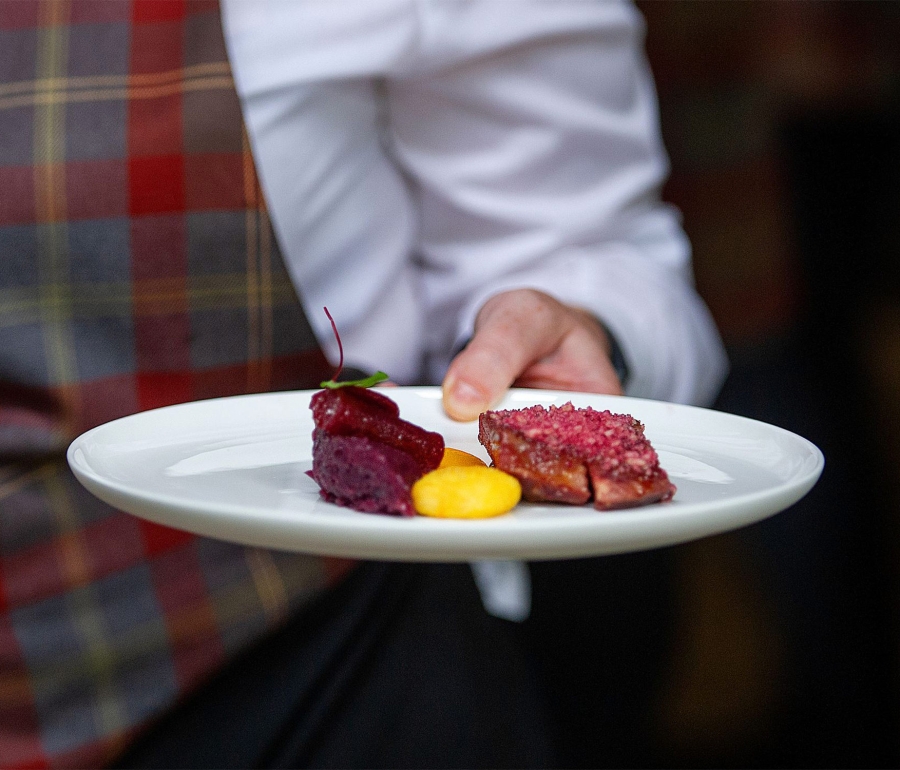 food sitting on a while plate being help by a server
