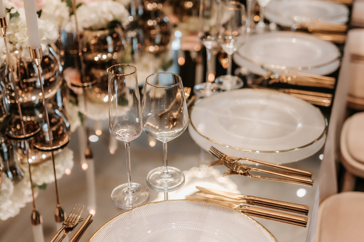 Elegant dining setup with plates and utensils on a glass table with candles in the center