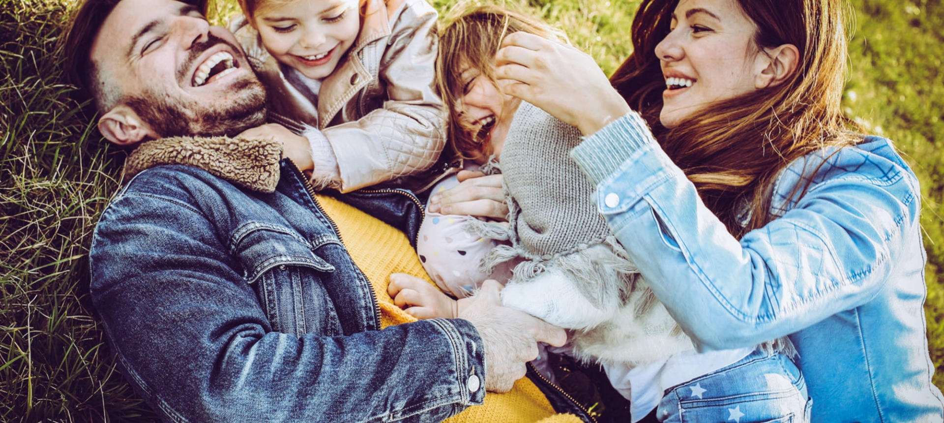 a beautiful family laying in the grass laughing and playing