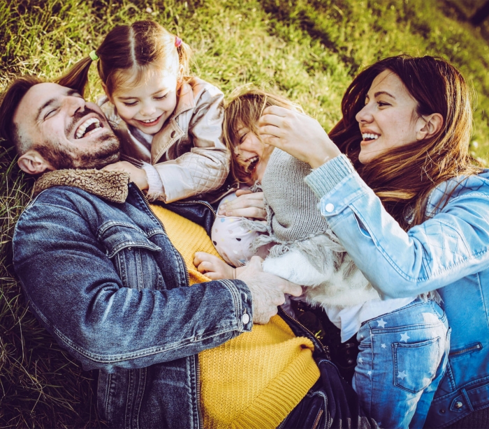 a beautiful family laying in the grass laughing and playing