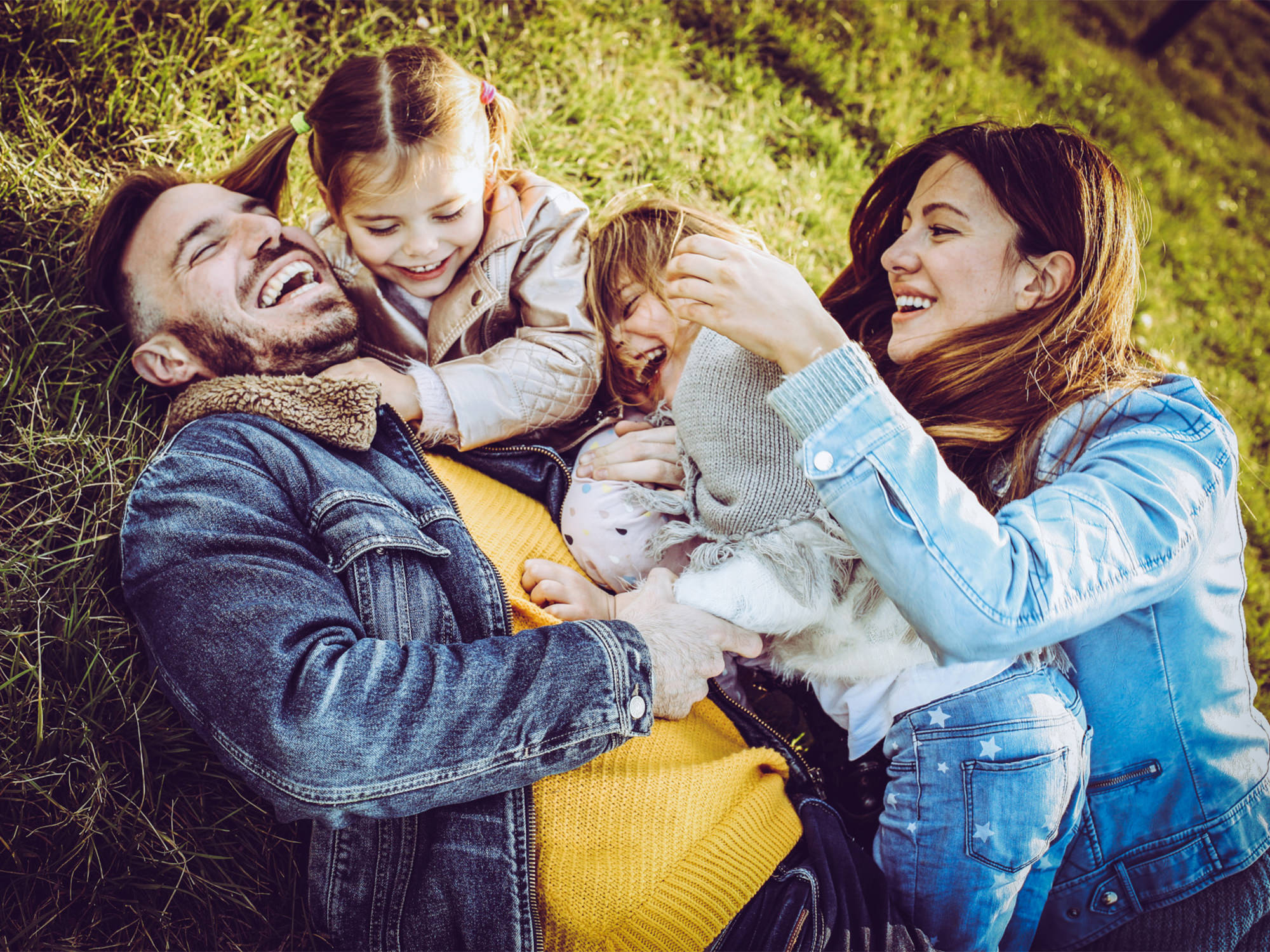 a beautiful family laying in the grass laughing and playing