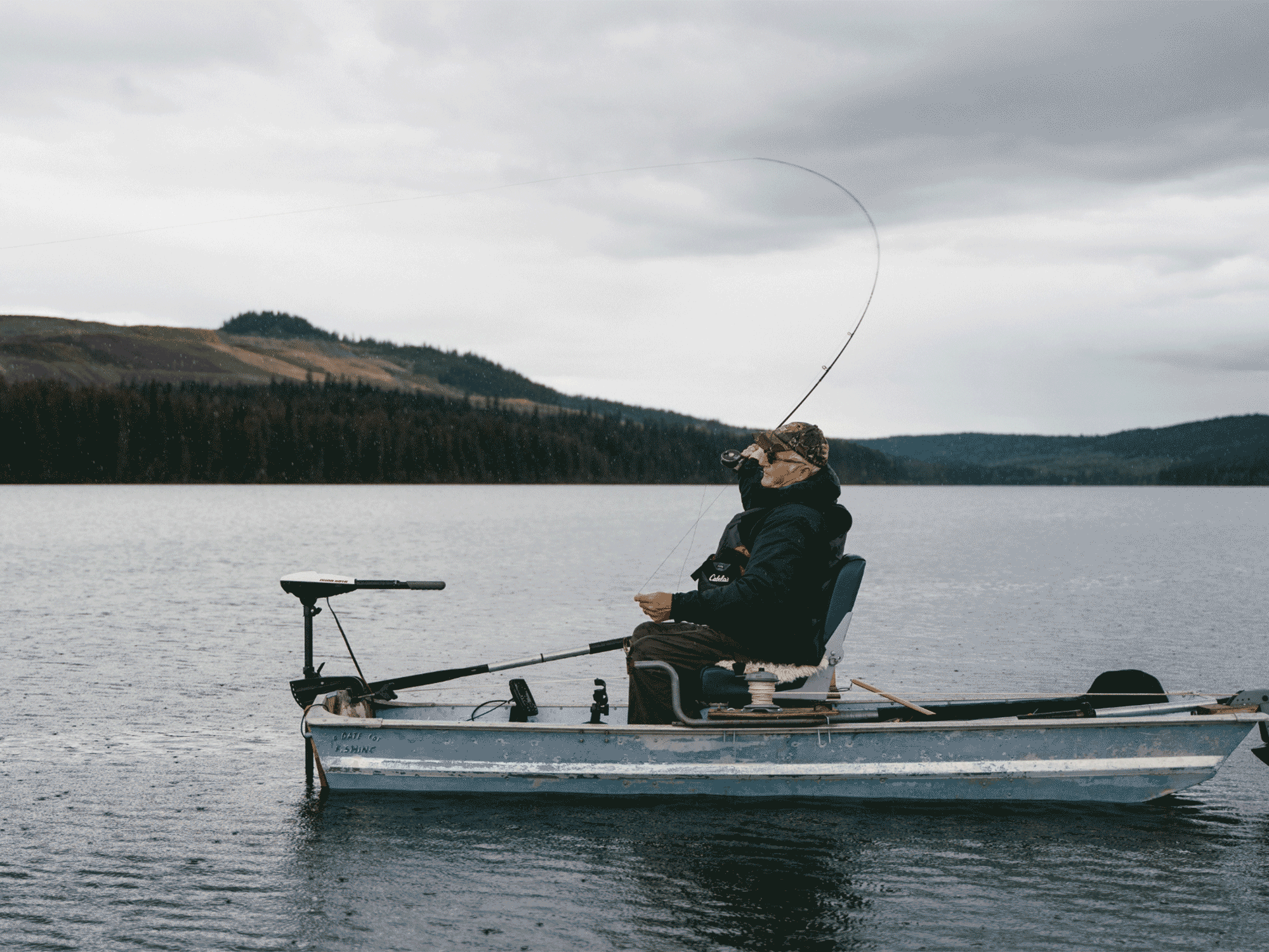 a old man sitting on a boat fishing in the middle of the water