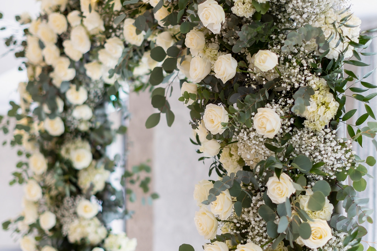 a large white flower arch inside of a wedding venue