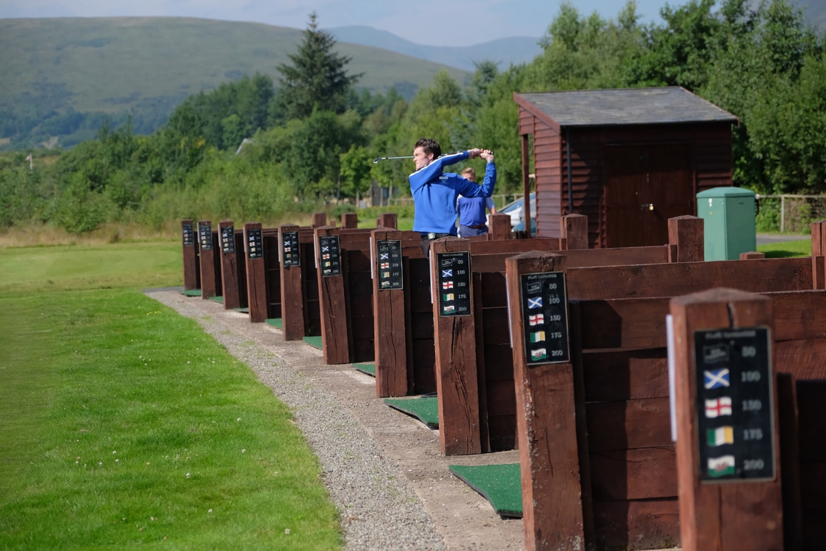a man practicing his golf swing at a out door driving range