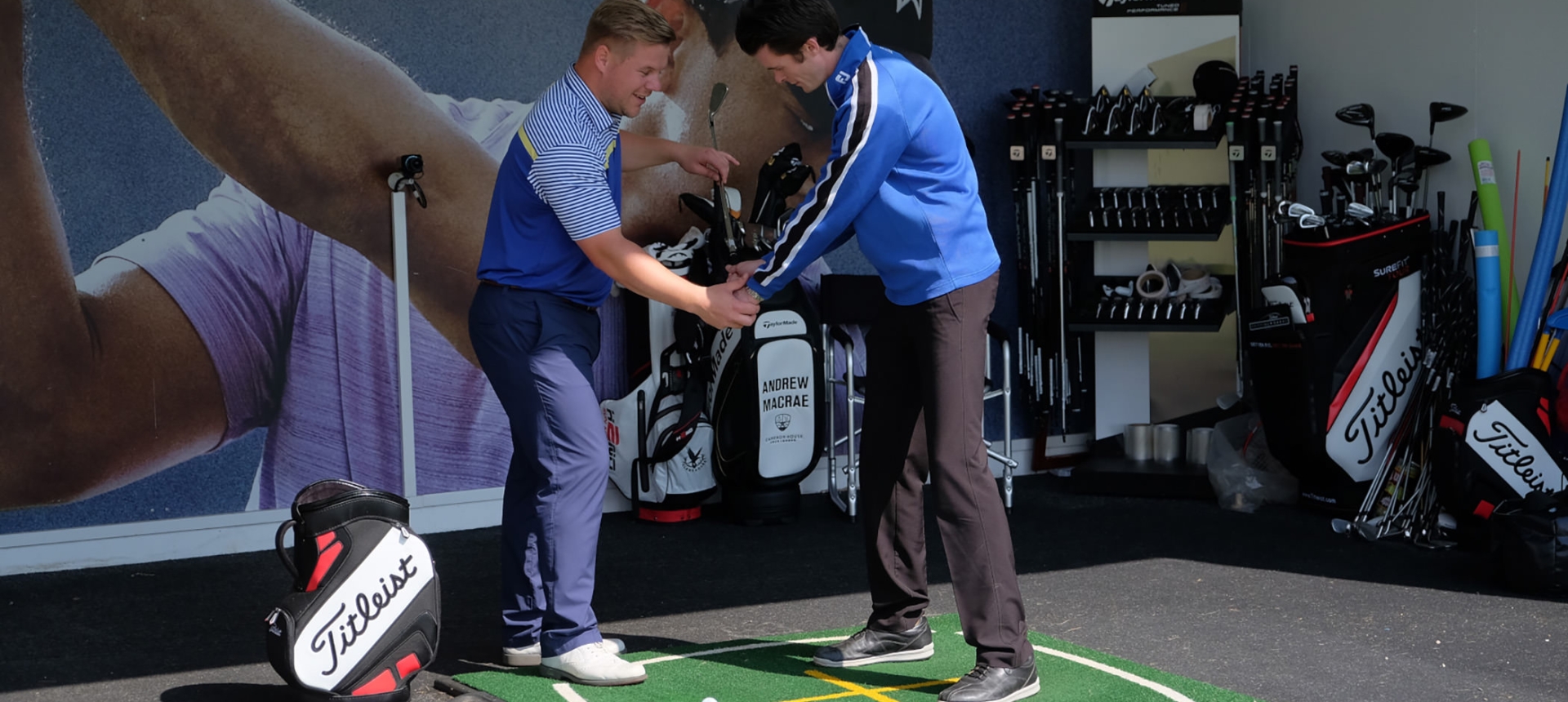 a man helping another man hold his club to practice his golf swing