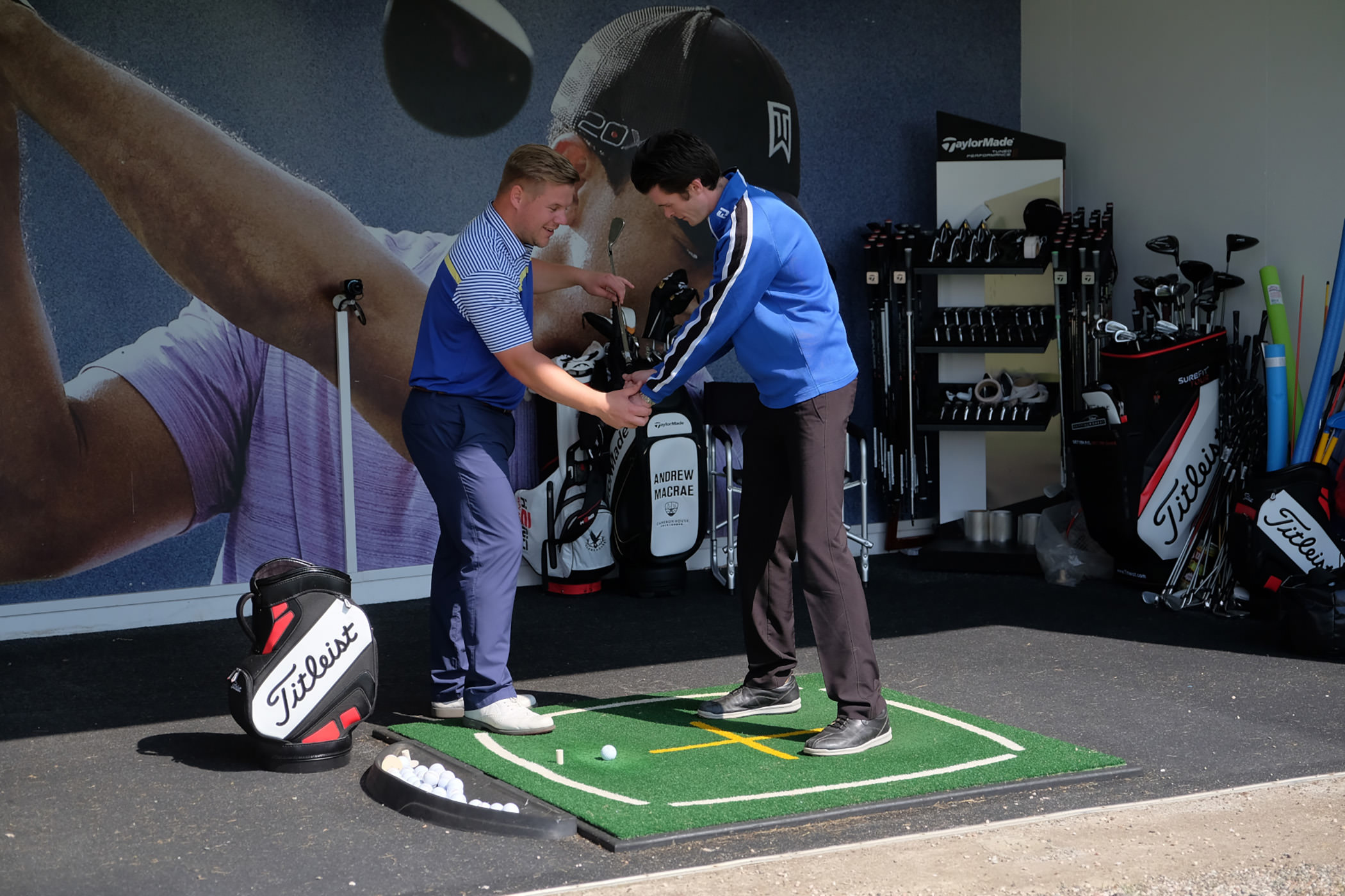 a man helping another man hold his club to practice his golf swing