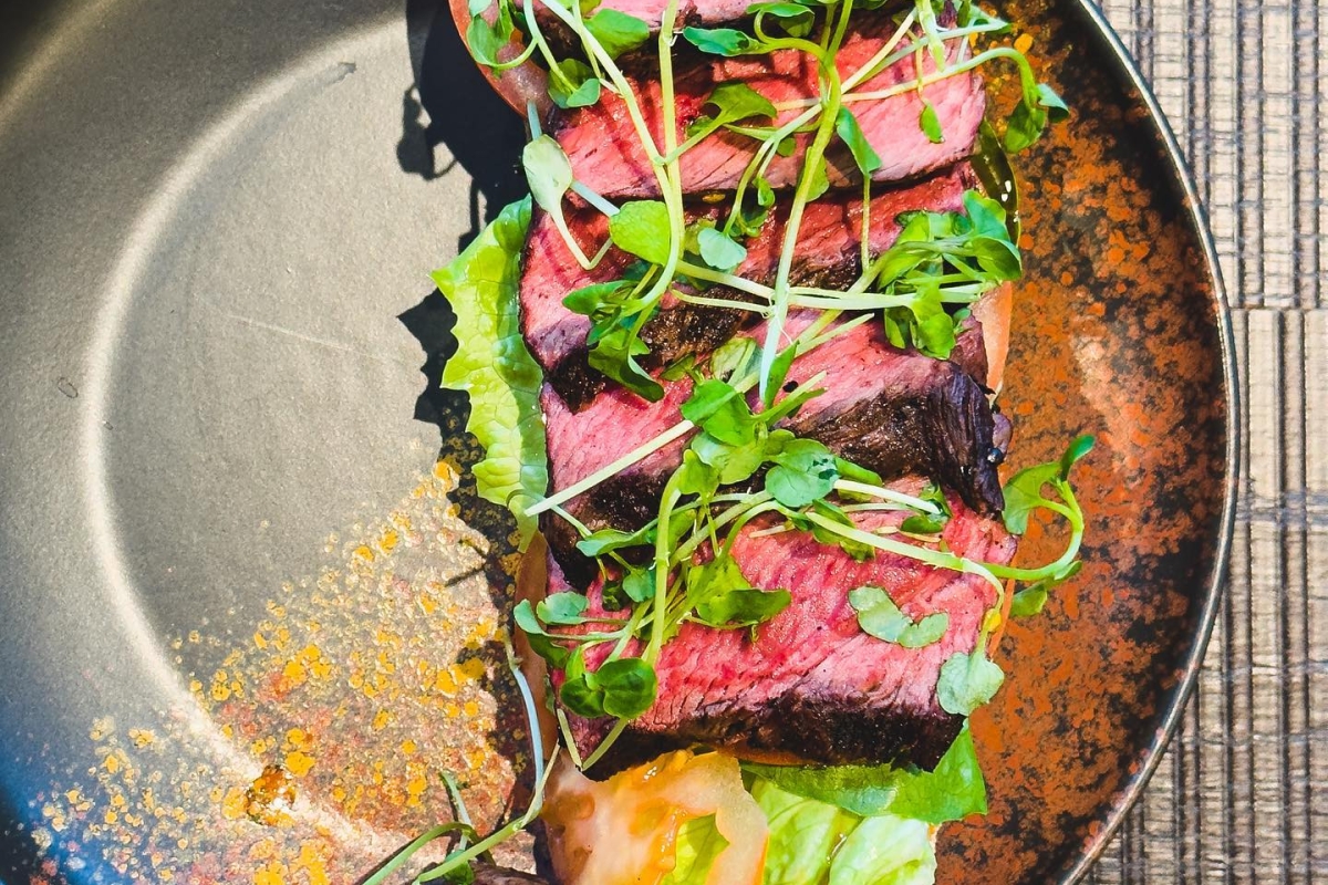 sliced up steak sitting on a black plate with colorful garnish