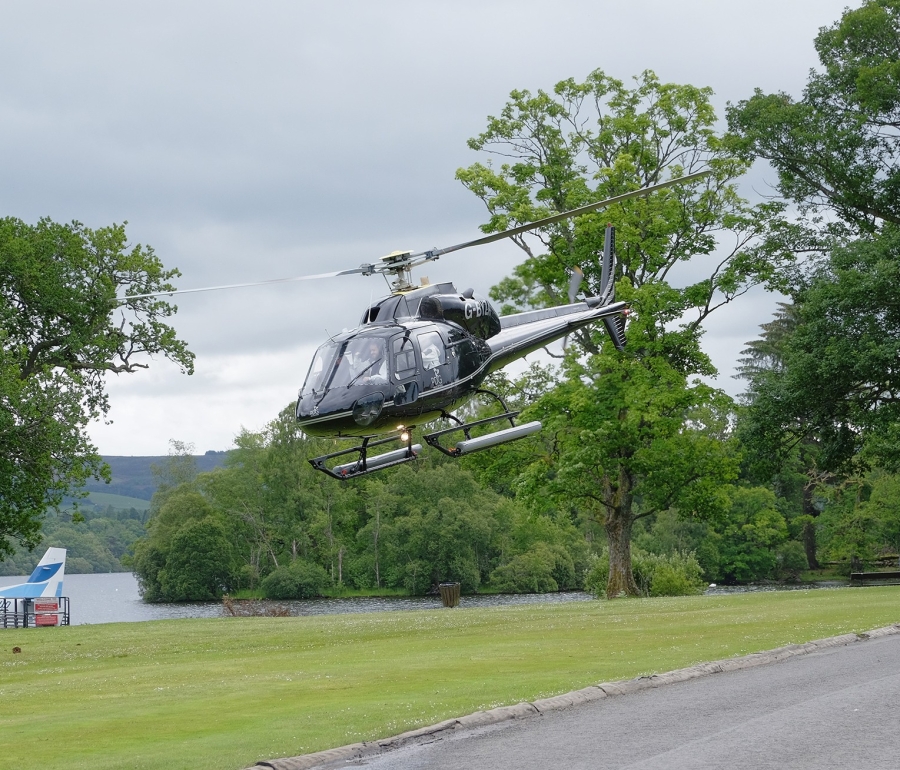 a black helicopter landing on a patch of grass