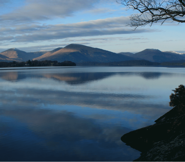 a body of water with mountains in the back ground on a cloudy night