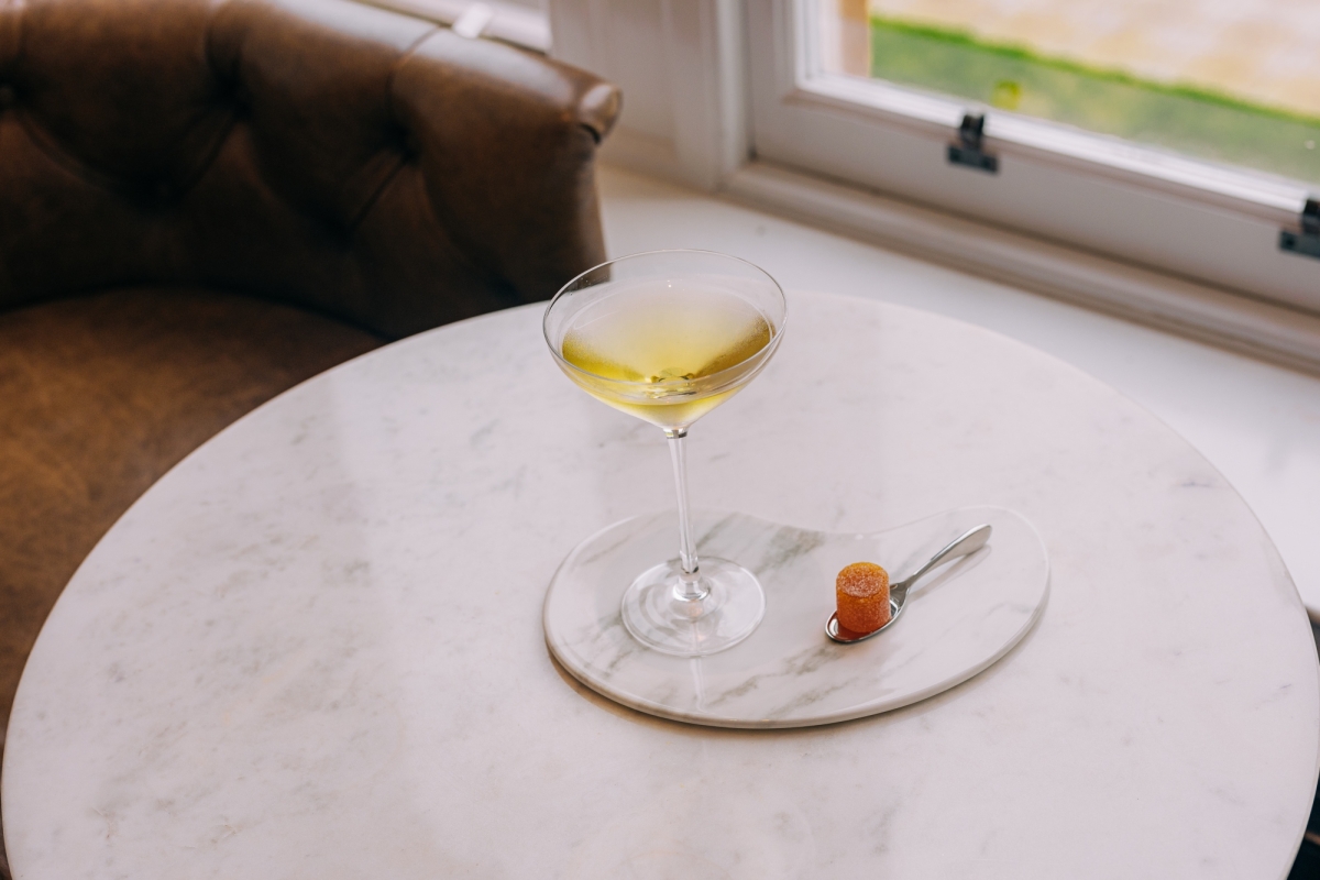 a martini sitting on a coaster with a brown chair next to it