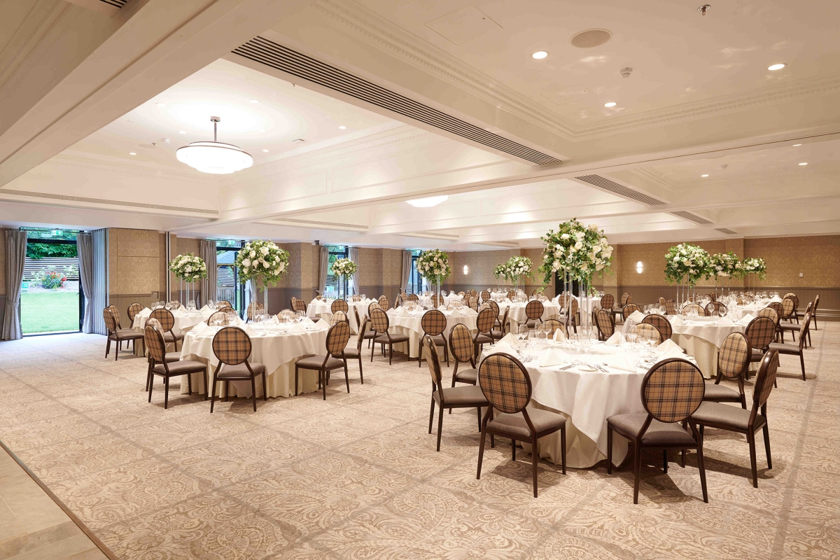 wedding space with tables and chairs along with floral arrangements standing tall over the tables