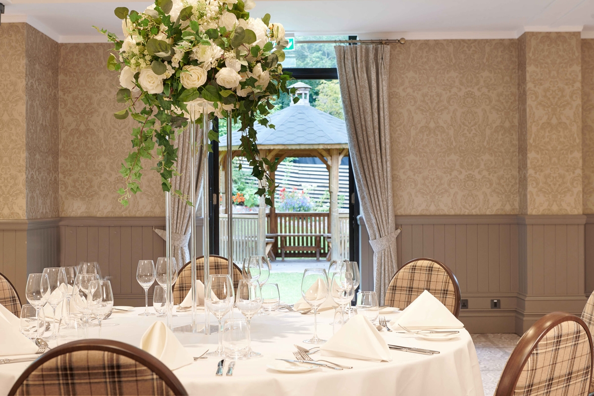 white table with chairs surrounding it and a large white floral arrangement and a gazebo outside an open door